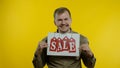 Great discounts. Happy cheerful blonde man in blue shirt showing Sale word advertisement inscription