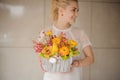 great easter flower arrangement in wicker basket with bright yellow flowers in woman& x27;s hands