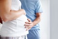 Great expectations. Side view of a pregnant woman holding her belly as the husband touches it in affection. Royalty Free Stock Photo