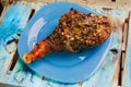 Great fresh baked turkey leg and sliced piece sprinkled with spices lying on a blue plate to black wooden background