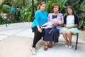 Great-grandmother with adult granddaughter and great-granddaughters sitting on bench, family portrait, copyspace