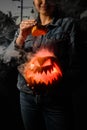 Great halloween pumpkin with burning and smoking mouth and eyes in female hands. Jack-o-lantern