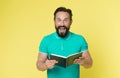 Great idea. Handsome inspired mature man holds notepad looking at camera while standing against yellow background. Man