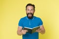 Great idea. Handsome inspired mature man holds notepad looking at camera while standing against yellow background. Man