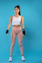 Great job of young sportwoman in stylish training outfit with jumping rope, ready for work. Full length on blue background with