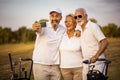 Great memories. Senior golfers using phone and taking self portrait. Focus is on background Royalty Free Stock Photo