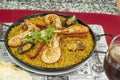 Great mixed Spanish summer paella for two with stewed chicken and prawns, crayfish and mussels, some red pepper and saffron on a