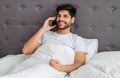 Great morning news. Happy arab man talking on smartphone with friend or lover, sitting in bed, copy space Royalty Free Stock Photo