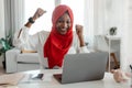 Great news. Excited african american muslim lady celebrating success, looking at laptop screen, raising fists and Royalty Free Stock Photo