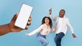 Great offer. Happy black couple dancing and looking at giant cell phone showing blank space for mock up Royalty Free Stock Photo
