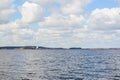 A great place for fishing: a large quiet  lake with calm wave under a cloudy sky, forest and urban houses on the horizon Royalty Free Stock Photo