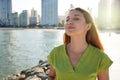 Great pleasure. Charming calm young woman is standing near sea with closed eyes and expressing delight. She is posing against