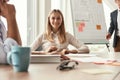 Great presentation. Young and cheerful woman looking at camera with smile while her boss standing near whiteboard and