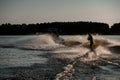 Great rear view of energy man riding wakeboard behind motor boat on splashing river waves. Active and extreme sports Royalty Free Stock Photo