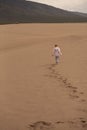 Young boy walking across sand dune with trail of footprints Royalty Free Stock Photo