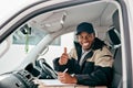 Great service is our promise to you. Portrait of a courier showing thumbs up while sitting in a delivery van. Royalty Free Stock Photo