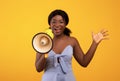 Great shopping offer. Millennial black woman yelling into megaphone, announcing big sale on orange studio background Royalty Free Stock Photo