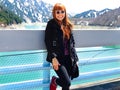 Pretty redhead woman smiling leaning agaisnt a bridge over a wonderful mountain background during a tour in Tateyama Kurobe Alpine Royalty Free Stock Photo