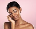 Great skin brings a smile to her face. Studio shot of a beautiful young woman posing with her eyes closed against a pink Royalty Free Stock Photo