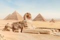 The great sphinx with the body of a lion and the face of a pharaoh lies on the sand against the background of all famous pyramids