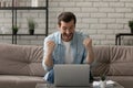 Euphoric young man sit by laptop shout super raise fists Royalty Free Stock Photo