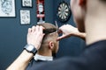 Great time at barbershop. Cheerful young bearded man getting haircut by hairdresser while sitting in chair at barbershop