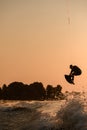 great view of active male rider holds rope and making jump on wakeboard at evening sky on background. Royalty Free Stock Photo