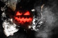 Great view on glowing handmade halloween pumpkin with smoking mouth and eyes which woman holds. Jack-o-lantern