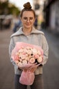 great view of handsome woman with luxury bouquet of pink roses in wrapping paper in the hand