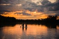 Great view of horizon and sunset and river on which pair of people swim on the sup boards