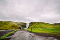 Great view of Skogafoss waterfall in Iceland and scenic surroundings.Tourists are looking at the huge flow of water.