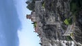 Great view of Varlaam monastery at Meteora, Thessaly, Greece with tourists rushing around and clouds and sunrays over the rocks -