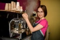 great view on woman barista stands at coffee machine and prepares drink