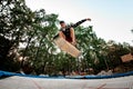 Great view young guy actively jumping with skateboard on trampoline