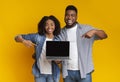 Great Website. Happy black couple pointing at laptop with black screen