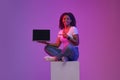 Great Website. Smiling Black Woman Pointing At Blank Laptop In Neon Light