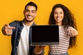 Great Website. Smiling middle eastern couple pointing at laptop with black screen