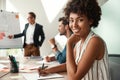 Great working day. Young afro american woman is looking at camera and smiling while her boss standing near whiteboard Royalty Free Stock Photo