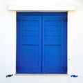 Greece, blue window shutters on white wall