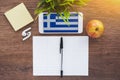 Greece flag, smartphone, wireless headphones, a notebook for writing foreign words on a working wooden table