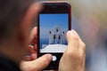 Greece, Santorini church picture appears on tablet, smartphone in man`s hands. Blurred background