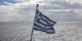 Greece sign symbol of leading shipping power in world. Greek waving flag on pole over sparkle sea Royalty Free Stock Photo