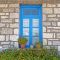 Greece, stone wall house blue window and marigold flowers Royalty Free Stock Photo