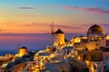 Greece vacation background. Famous iconic Oia village with traditional white houses and windmills during colorful sunset. Royalty Free Stock Photo