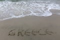 Greece writing on the sand with water coming to erase it