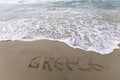 Greece writing on the sand with water coming to erase it