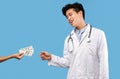 Greedy asian male doctor taking bribe from female patient Royalty Free Stock Photo