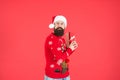 Greedy bearded guy wearing funny knitted sweater and santa claus hat and hold present box has an idea for celebrating