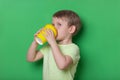 Greedy child boy look back drinking coffee from yellow disposable cup on green background Royalty Free Stock Photo