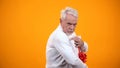 Greedy male pensioner embracing giftbox and seriously looking on camera, avarice Royalty Free Stock Photo